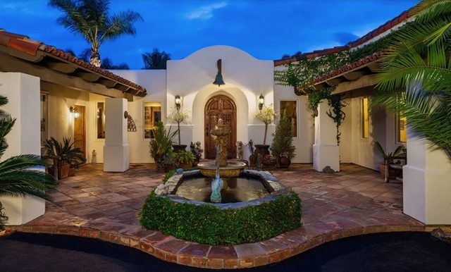 Courtyard entry of a Spanish-style North County home at dusk, lit and quiet