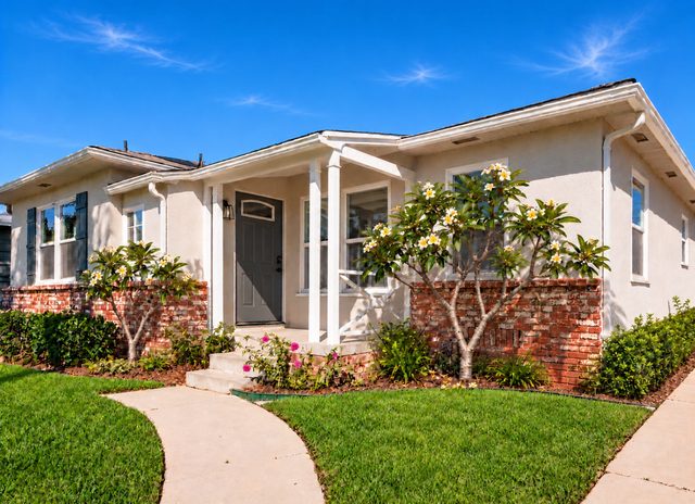 Coastal cottage with a plumeria tree and a freshly kept front lawn